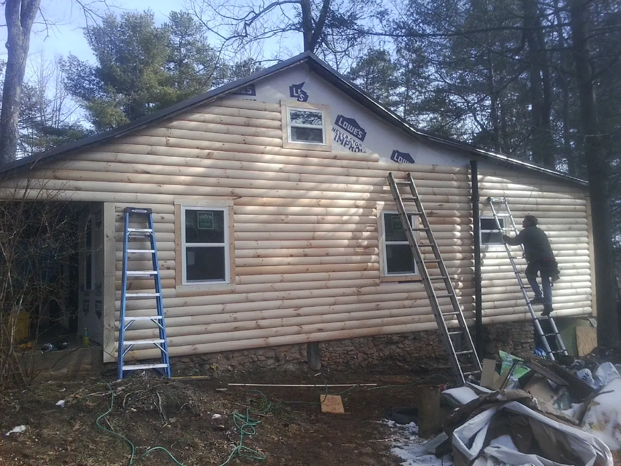 Ladders set against fresh log siding during an exterior remodel in Santa Fe