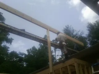 Carpenter setting a ridge beam over a new addition frame — Ice Dam Removal by Roofing Brothers in Santa Fe
