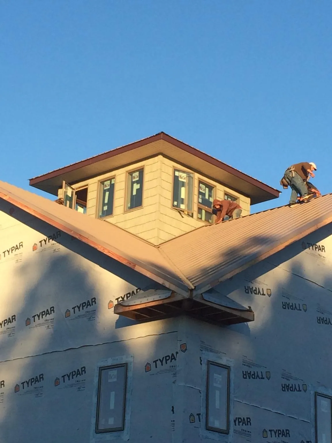 Roofers working around a rooftop cupola on a new metal roof at sunset — Roof Waterproofing in Santa Fe by Roofing Brothers